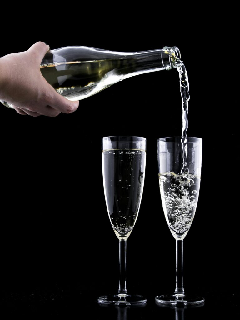 Elegant champagne being poured into two flutes against a black background, highlighting celebration and luxury.